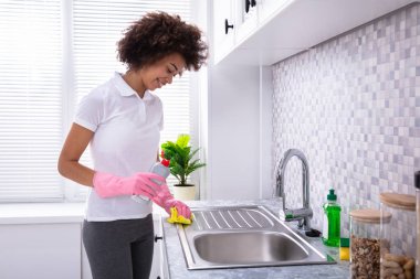 Mutlu genç kadın hademe evye sünger ile Temizleme