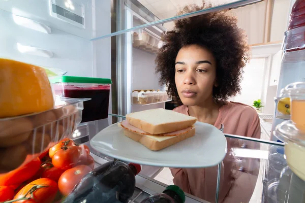 オープン冷蔵庫の食品を探してアフリカ若い女性のクローズ アップ — ストック写真