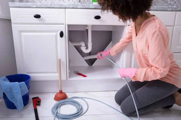 Una Mujer Joven Limpieza Atascado Fregadero Tubería Con Cable Drenado — Foto de Stock