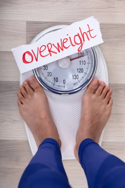 白い紙の上に太りすぎを示す体重計に女性の足のクローズアップ — ストック写真