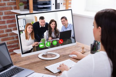 Bilgisayarda bir genç iş kadını video konferans onun meslektaşları ile yan görünüm