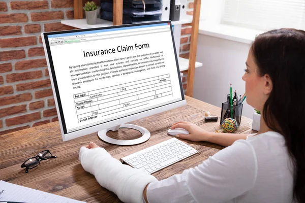 Businesswoman Plaster Cast Hand Filling Insurance Claim Form Computer Office — Stock Photo, Image