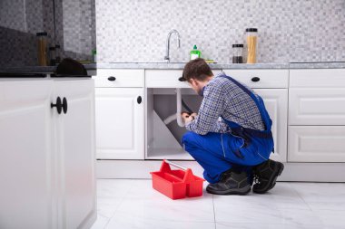 Erkek Tesisatçı Kırmızı Alet Kutusunun yanı sıra Mutfakta Lavabo Tamiri