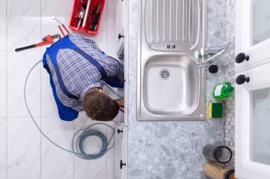 Genç erkek tesisatçı temizlik mutfak lavabo boru tıkanmış