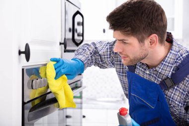 Mutfakta fırın temizleyen hizmetlinin yakın çekimi.