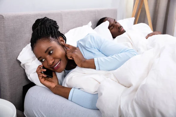 Joven Mujer Africana Hablando Por Celular Mientras Marido Duerme Cama — Foto de Stock