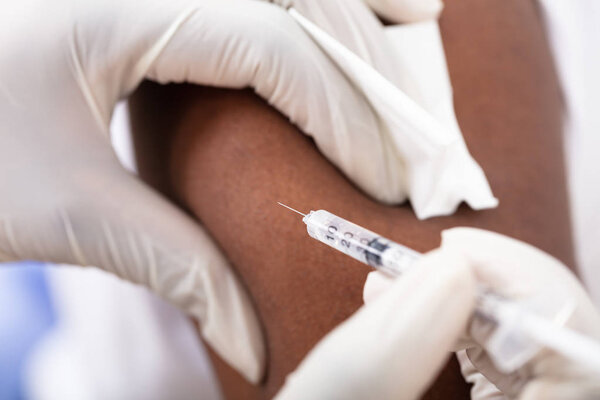 Close-up Of A Doctor Injecting Syringe To Male Patient's Arm In Clinic