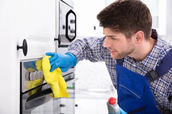 Mutfakta fırın temizleyen hizmetlinin yakın çekimi.