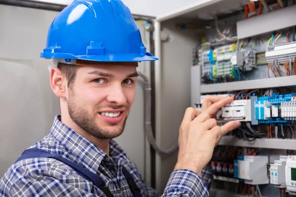 Genç teknisyen tornavida ile sigorta kutusu tamir yan görünüm