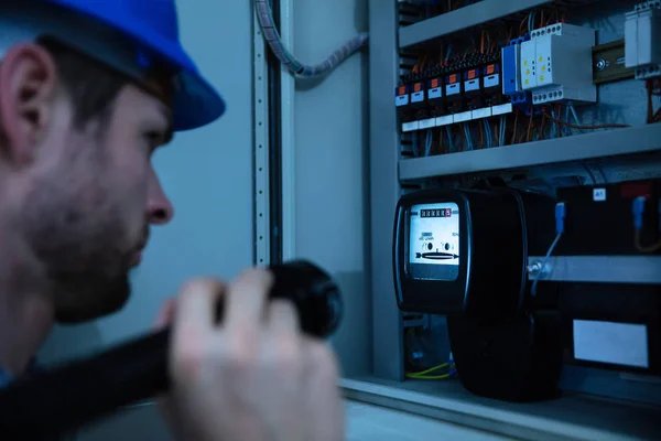 Nahaufnahme Eines Elektrikers Der Einen Sicherungskasten Mit Einer Taschenlampe Untersucht — Stockfoto