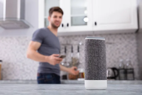 Close-up Of Wireless Speaker In Front Of Man Cutting Vegetables In Kitchen