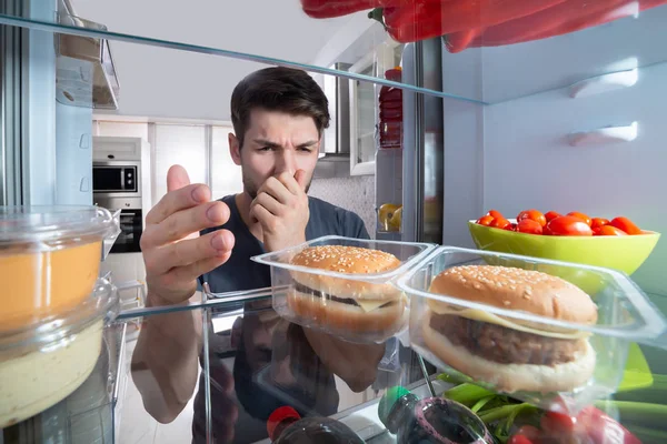 Молодой Человек Держащий Нос После Распознавания Неприятного Запаха Исходящего Холодильника — стоковое фото