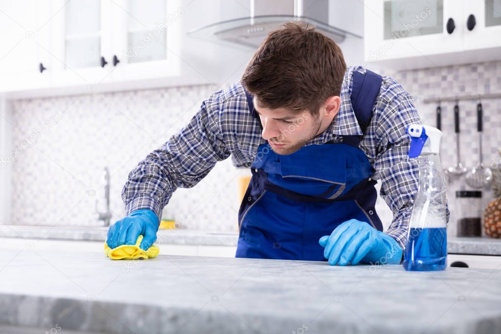 Close-up Of A Young Man Cleaning Dirty Kitchen Counter With Napkin