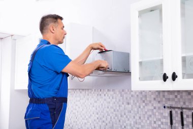 Erkek teknisyen dijital multimetre ile Extractor süzgecinde mutfak kontrol yükseltilmiş görünümünü