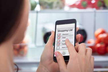 Alışveriş listesi cep telefonunda işaretleme bir kadın eli Close-up