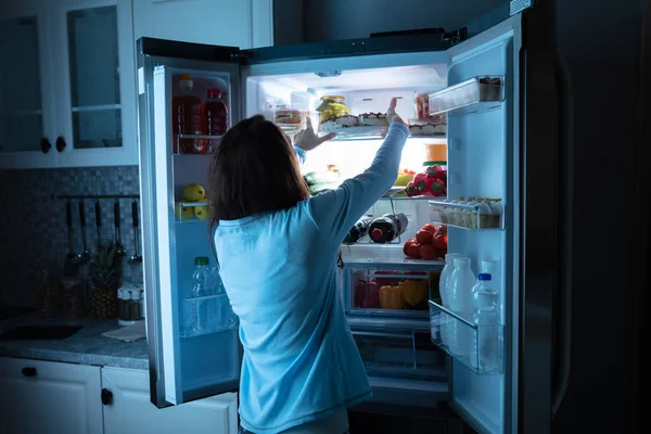 冷蔵庫に食品を保つ女性の後姿 — ストック写真