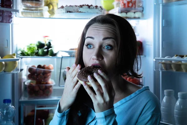 Close Uma Jovem Mulher Comendo Donut Frente Refrigerador Aberto — Fotografia de Stock