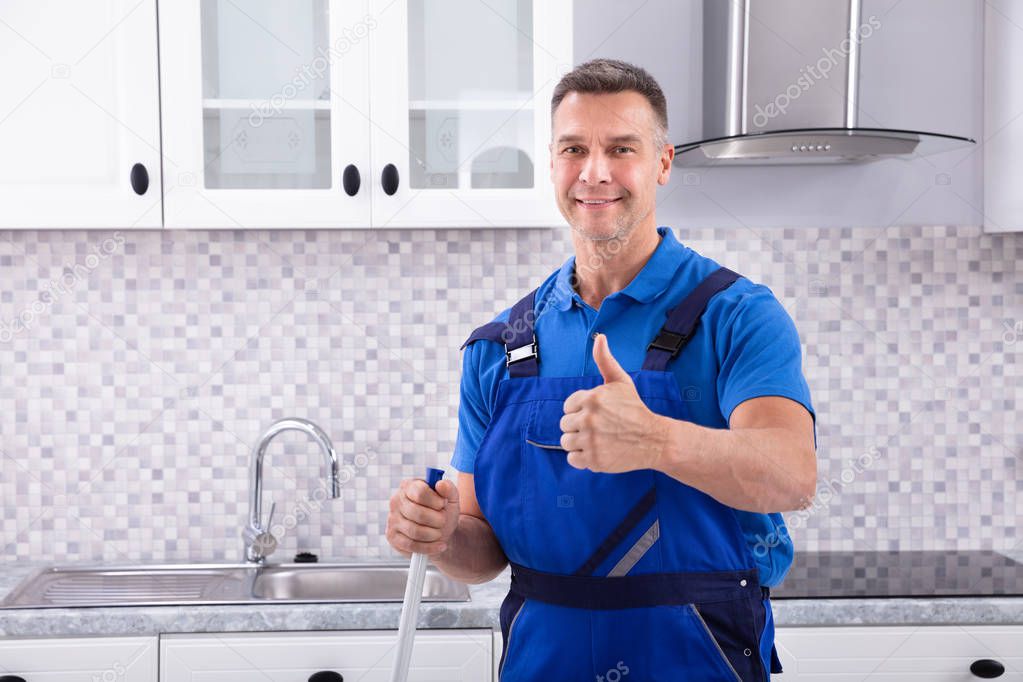 Portrait Of A Happy Male Janitor Gesturing Thumbs Up In Kitchen