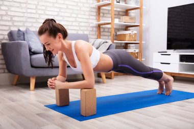 Genç kadın egzersiz Yoga Mat ahşap bloklar kullanarak uygun