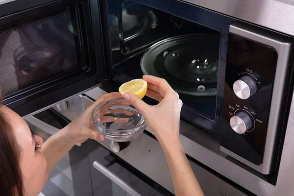 Woman Putting Sliced Lemon Bowl Open Microwave Oven — Stock Photo, Image