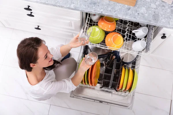 若い女性の家に食器洗い機で皿を配置を笑顔 — ストック写真