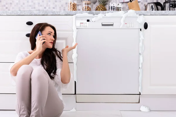 Сумна Жінка Телефонує Технік Мобільний Телефон Щоб Виправити Посудомийну Машину — стокове фото