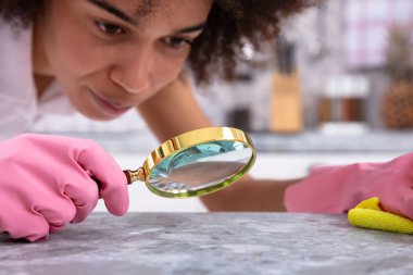 Mutfak tezgahı büyüteç ile bakarak pembe eldiven giymiş genç bir kadın portresi