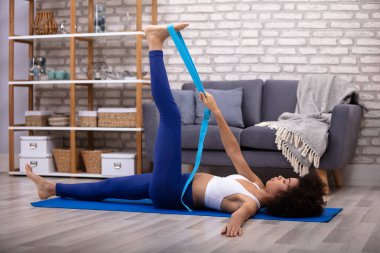 Afrika genç kadının egzersiz Fitness mat yaparken egzersiz Yoga kemer germe yapması