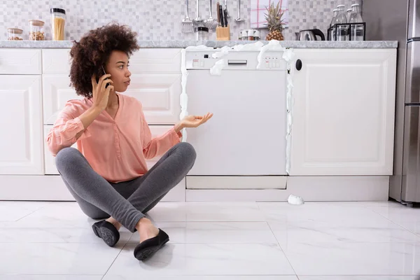 Smutná Žena Volající Technik Mobilní Telefon Opravit Myčka Nádobí Pěnou — Stock fotografie