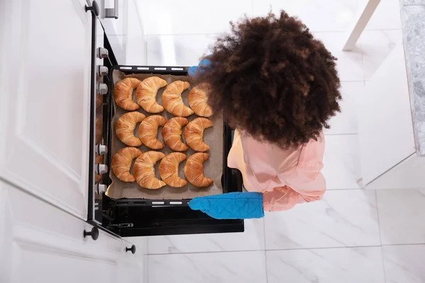 Happy Young Woman Wearing Blue Mitt Removing Baked Croissants Tray — Stock Photo, Image