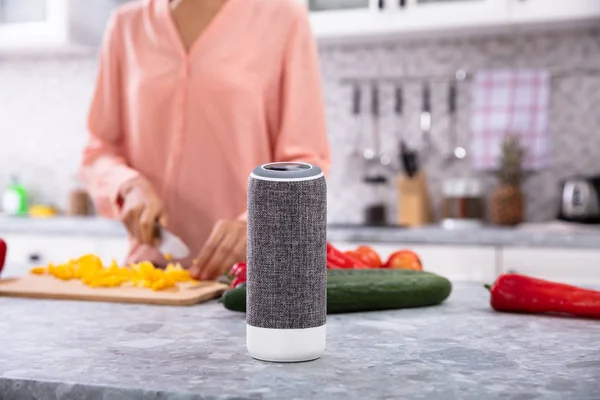 Close-up Of A Woman Working In Kitchen With Smart Speaker In Foreground