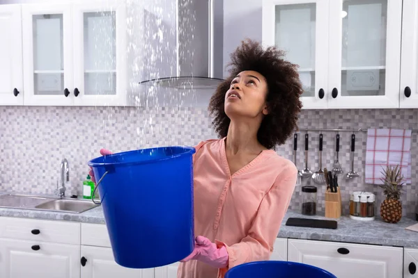 Close Worried Young Woman Collecting Water Leaking Ceiling Blue Bucket — Stock Photo, Image