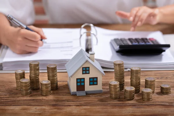 Moedas Empilhadas Modelo Casa Mesa Frente Empresária Que Calcula Fatura — Fotografia de Stock