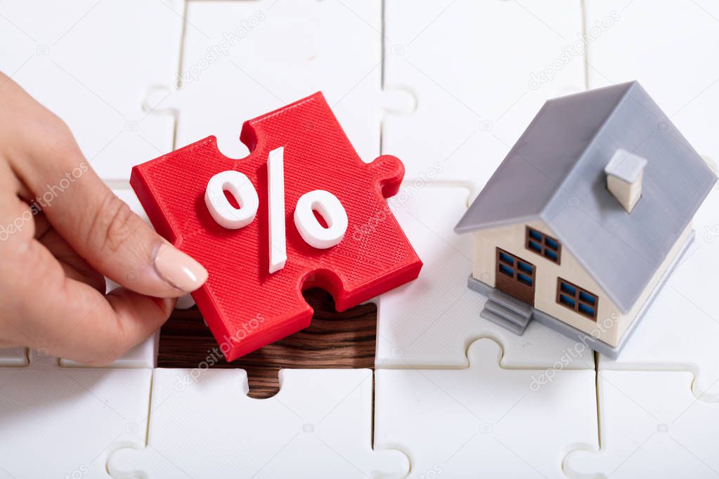 An Overhead View Of A Person Holding Percentage Puzzle Pieces Near The House Model