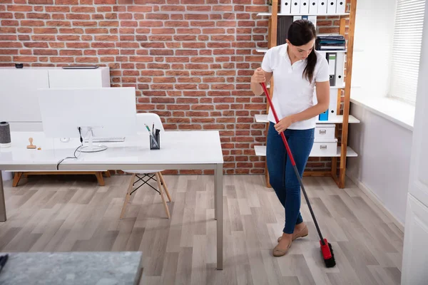 Glücklich Jung Weiblich Janitor Putzen Fußboden Mit Besen Büro — Stockfoto