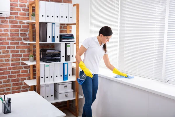 Young Woman Cleaning Window Sill Napkin Spray Bottle Office — Stock Photo, Image