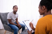 Mladý africký muž sedí na židli u ženské psycholog s schránky