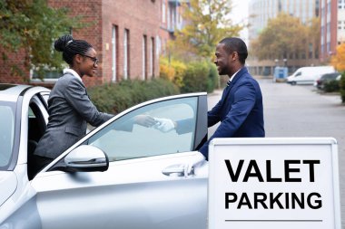 Arabanın anahtarını erkek Vale yakınındaki Valet Parking işaret vererek gülümseyen iş kadını