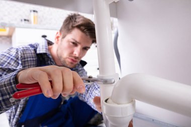 Genç erkek tesisatçı lavabo boru ayarlanabilir anahtarı ile onarma