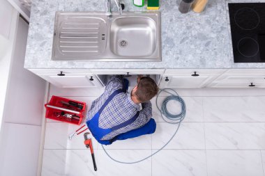 Genç erkek tesisatçı temizlik mutfak lavabo boru tıkanmış