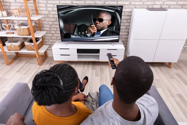 Ευτυχισμένο Αφρικανικό Ζευγάρι Κάθεται Στον Καναπέ Βλέποντας Τηλεόραση Στο Σπίτι — Φωτογραφία Αρχείου