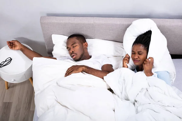 Mujer Africana Perturbada Cubriéndose Los Oídos Con Almohada Mientras Marido — Foto de Stock