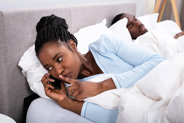 Jovem Mulher Africana Falando Celular Enquanto Seu Marido Dormindo Cama — Fotografia de Stock