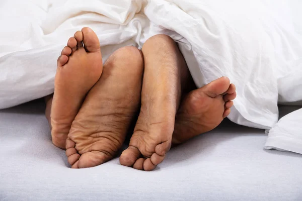 Çiftin Beyaz Battaniyenin Altındaki Çıplak Ayakların Yakın Çekimi — Stok fotoğraf