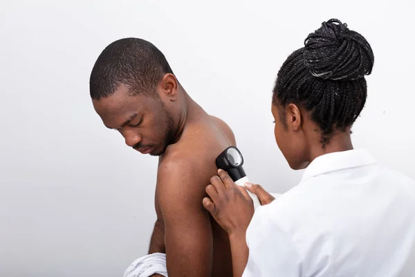 Genç Afrikalı Kadın Doktor Erkek Sırtındaki Pigmentli Deriyi Dermatoskopla Ncelerken — Stok fotoğraf