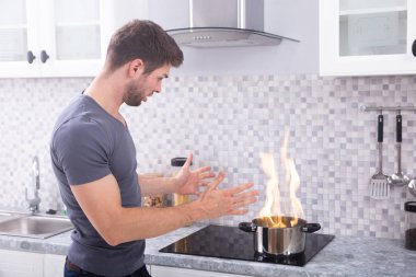 Yanan ateşe indüksiyon ocağı ile tencereye arayan genç adam şok