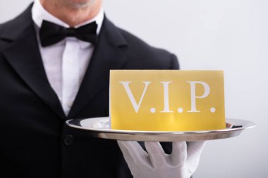 Close-up Of A Waiter Showing Vip Text Banner Against White Background clipart