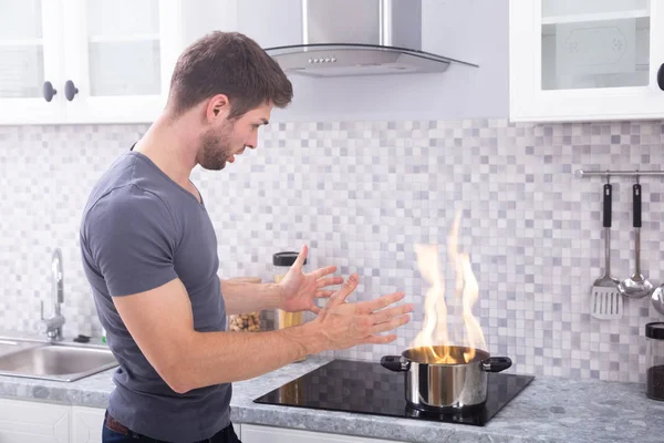 Schockierter Junger Mann Sieht Brennenden Kochtopf Auf Induktionsherd — Stockfoto