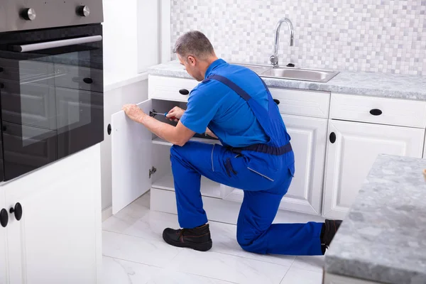 Side View Male Handyman Fixing Cabinet Door Using Screwdriver Kitchen — стоковое фото