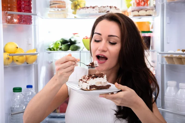 Närbild Kvinna Äter Tårta Nära Öppen Kylskåp — Stockfoto